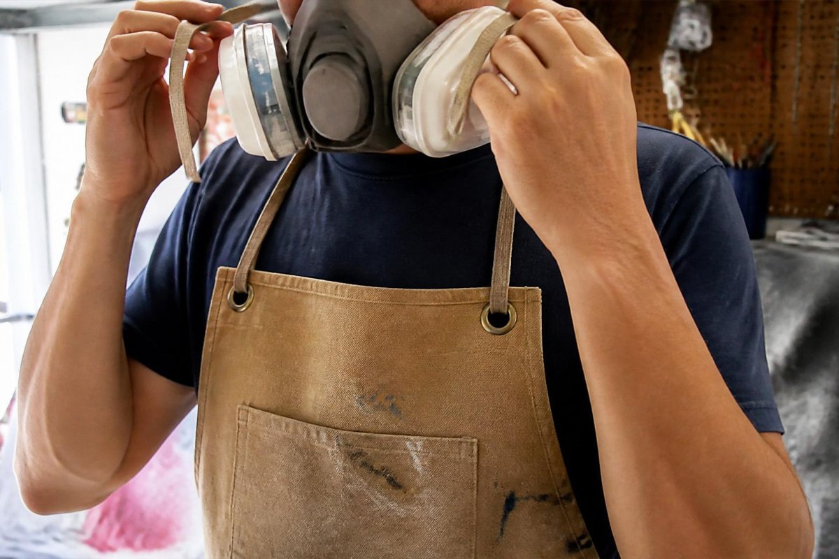 person fitting half-face respirator mask before spray painting